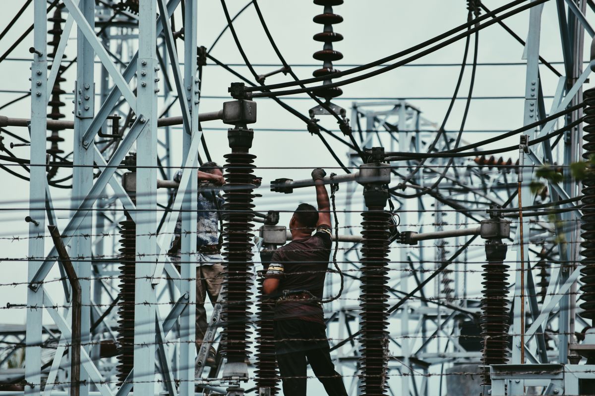 Technicians working on high voltage equipment at an electrical substation