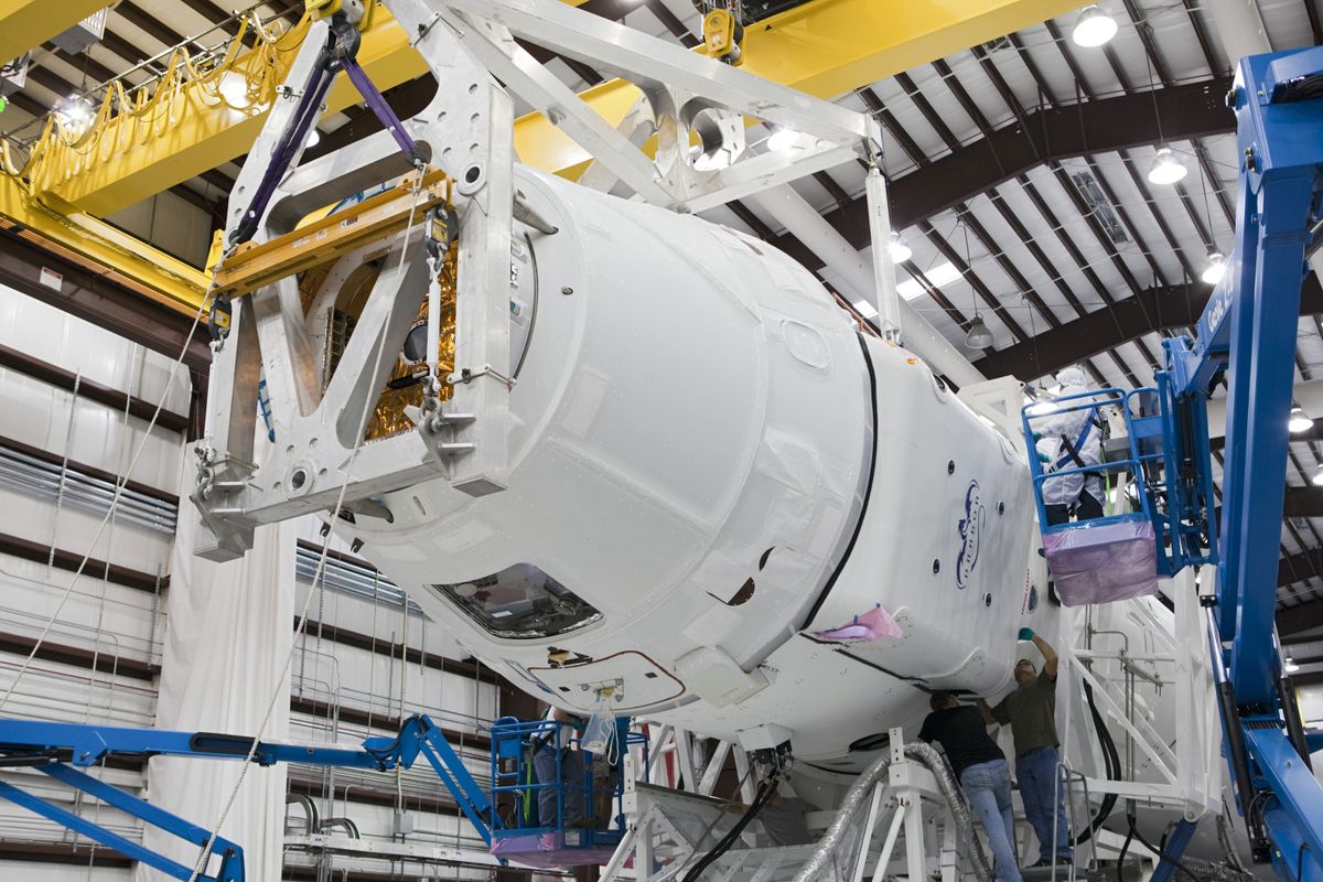 Engineers assembling a spacecraft capsule in an integration hall